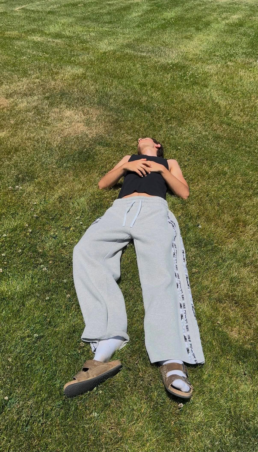 Model laid out on grass wearing wide-leg sweats