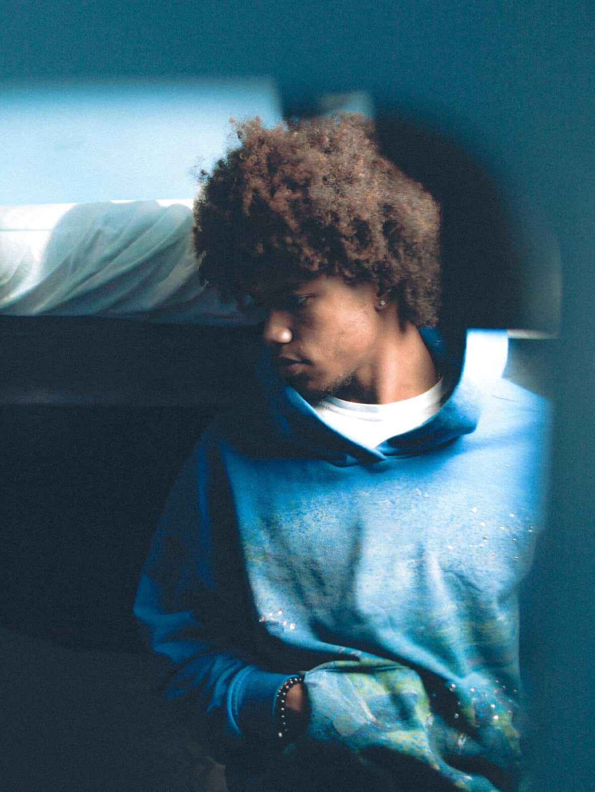 Hand-finished hoodie photographed in blue tungsten light